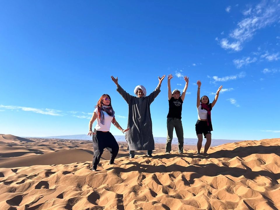 Guests and their desert guide on the dunes of the Moroccan Sahara
